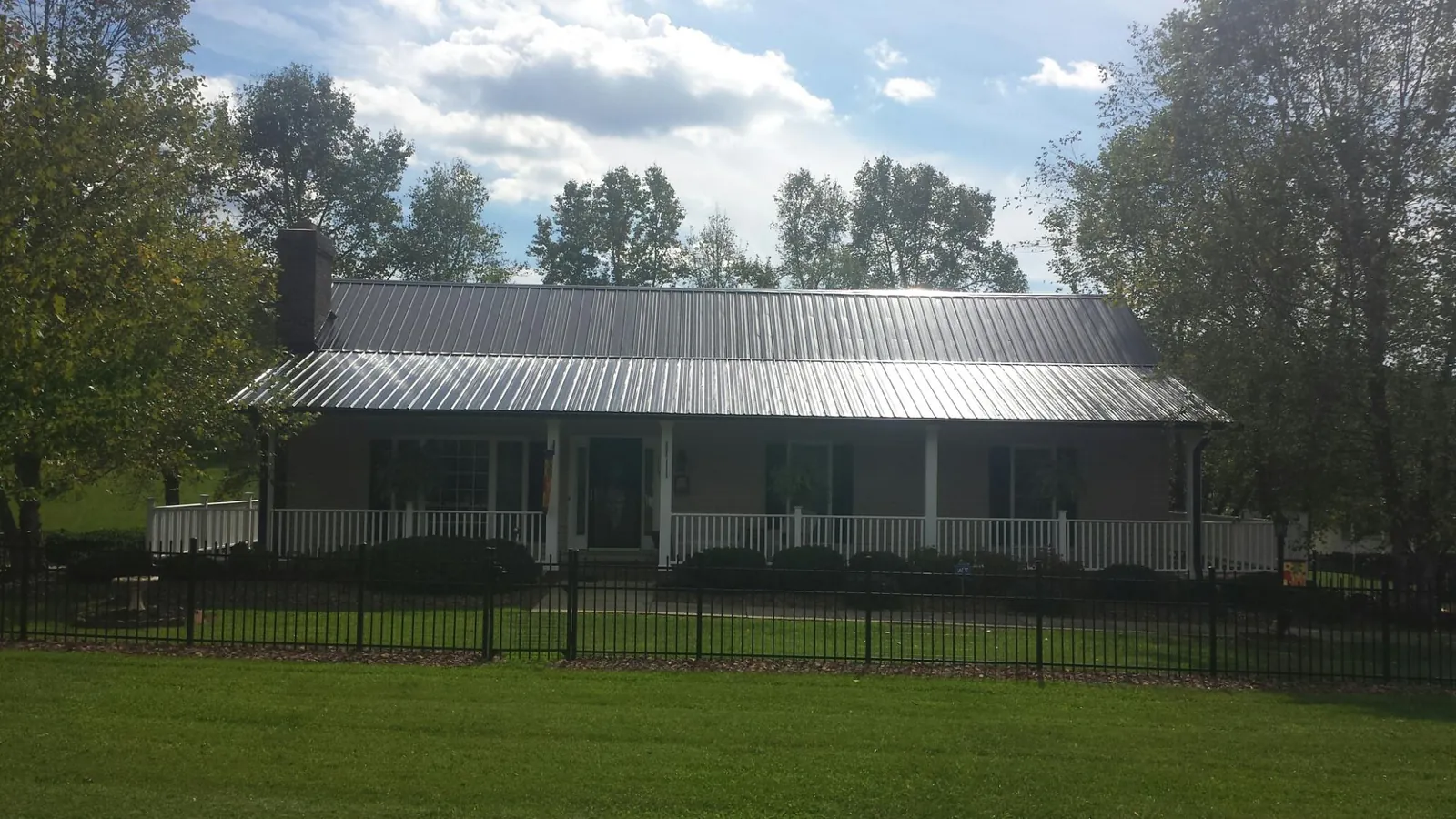 Gray metal roof on a brick ranch with a full width front porch — Gutter Guard Installation work by our crew in Shepherd