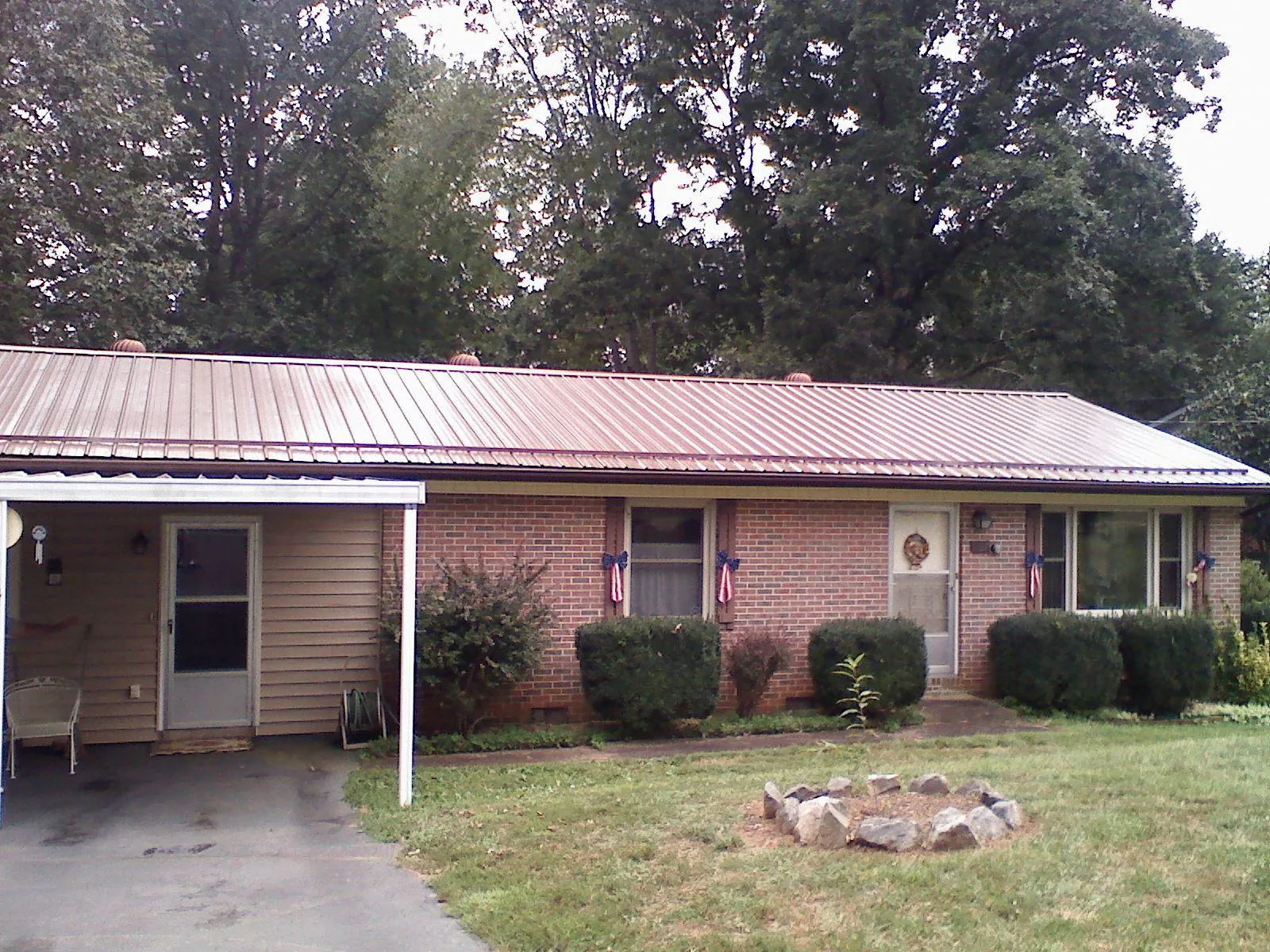 Bronze metal roof and carport on a brick ranch home — Roof Repair work by our crew in Shepherd