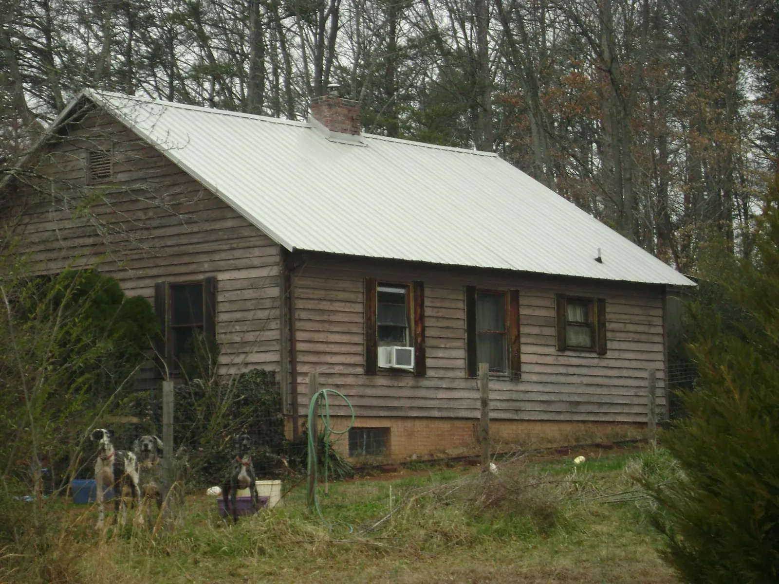 White metal roof on an old wood sided farmhouse, from a Metal Roof Installation job in Shepherd
